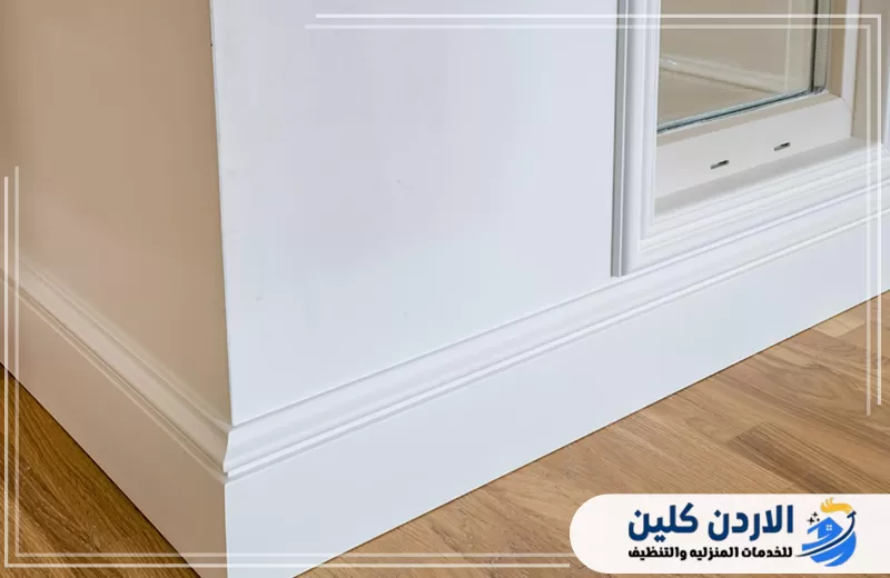 نعلات أرضية بيضاء مركبة حول الجدار وأسفل النافذة بما يتناسق مع الأرضيات والديكور الداخلي.