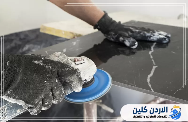 عامل يستخدم أداة تلميع على لوح رخامي داكن لمعالجة الحواف والسطح وتحسين اللمعة وإزالة آثار الاستخدام.