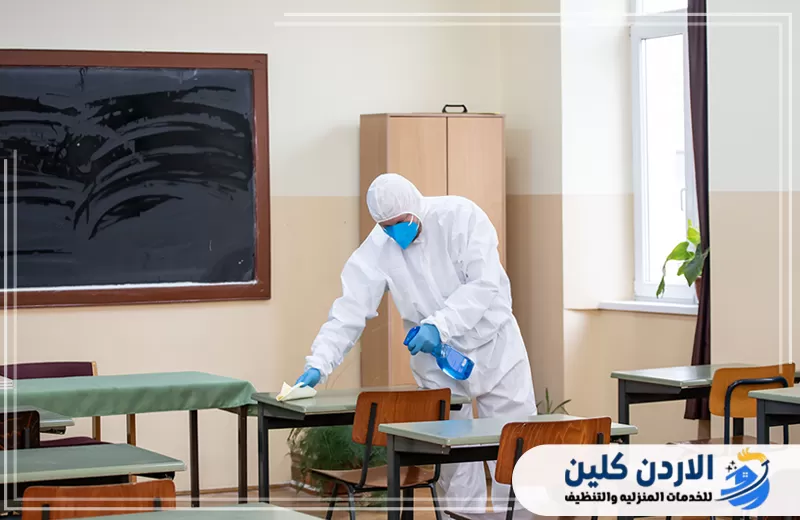 تعقيم الطاولات والكراسي داخل الفصل ضمن أعمال تنظيف المدارس للحفاظ على بيئة صحية للطلاب.