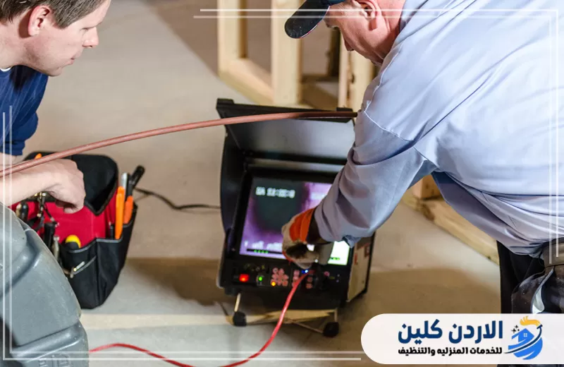 فنيان يستخدمان جهاز فحص بالكاميرا لمعاينة خطوط الصرف داخل المبنى وتحديد موقع المشكلة بدقة قبل بدء الإصلاح.