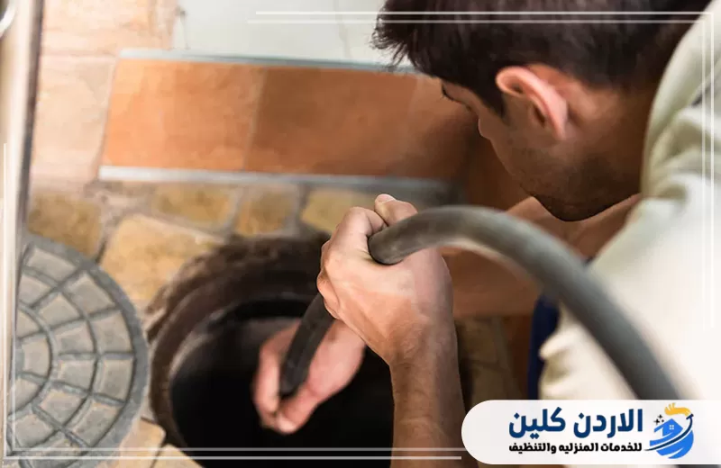 فني يُدخل خرطوم التسليك داخل فتحة الصرف لمعالجة الانسداد وتنظيف المجرى الداخلي.