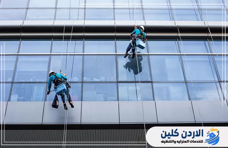 احجز تنظيف واجهات المباني المرتفعة مع الأردن كلين 0798779667. فنيون ينفذون تنظيف واجهة زجاجية لمبنى مرتفع باستخدام الحبال ومعدات السلامة المخصصة للعمل على الارتفاعات.