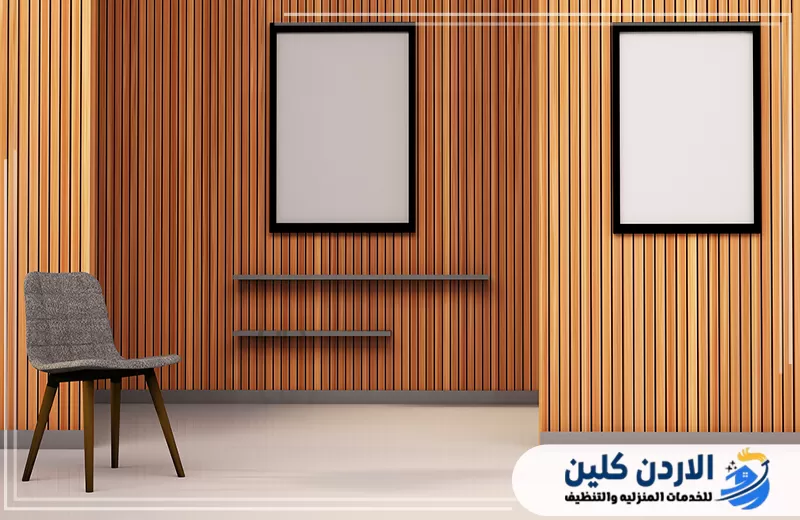 احجز تصميم وتنفيذ جدار بديل خشب متناسق لمنزلك 0798779667. غرفة داخلية مزينة بجدار من الشرائح الخشبية مع رفوف وإطارات توضح استخدام بديل الخشب في الديكور السكني الحديث.