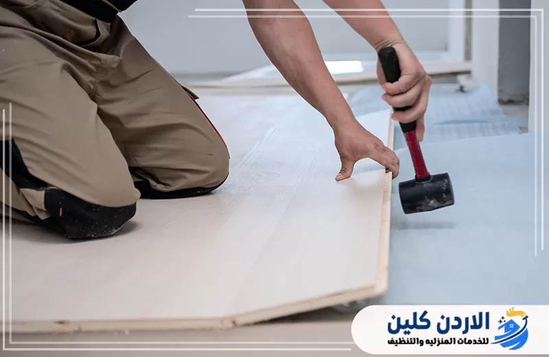 فني يستخدم أداة التثبيت لضبط ألواح الأرضية وإغلاق الفواصل أثناء صيانة أرضيات الباركيه داخل المنازل.