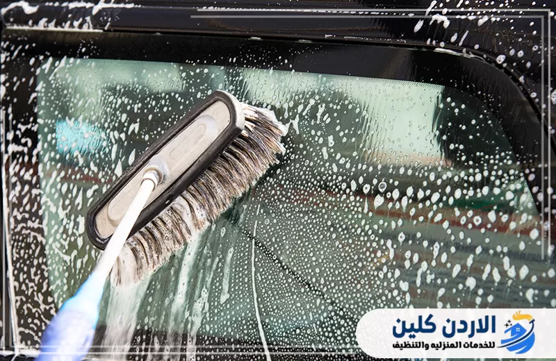 تنظيف زجاج السيارات في الأردن بالفرشاة والرغوة لإزالة الغبار والبقع المتراكمة.