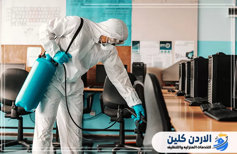 تعقيم الكراسي والمكاتب داخل قاعة عمل تحتوي على أجهزة كمبيوتر ومناطق استخدام متكرر.