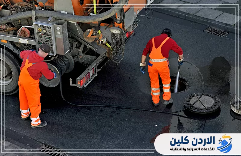 عاملان يستخدمان سيارة شفط مجهزة لتنظيف المناهل وسحب مياه الصرف من الشبكة.