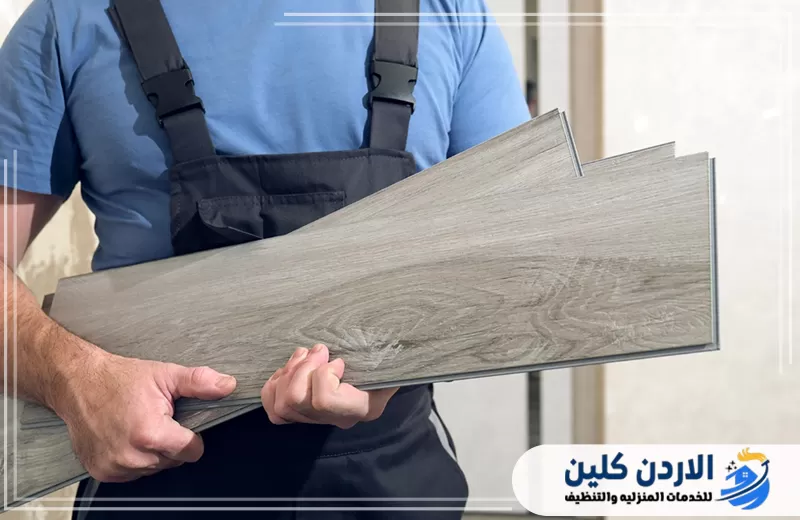 فني يحمل ألواح أرضيات SPC جاهزة للتركيب، ما يوضح تجهيز الخامات قبل بدء التنفيذ داخل الموقع.