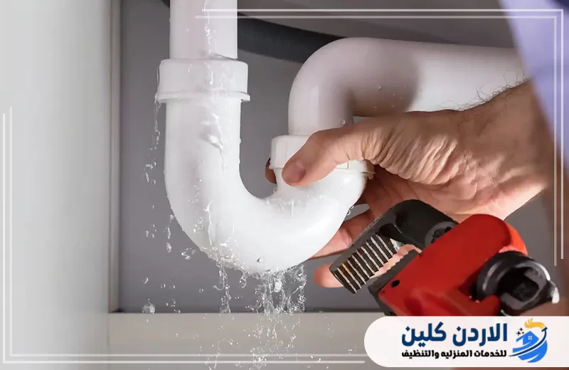 تسرب مياه من ماسورة الصرف أسفل الحوض أثناء تنفيذ أعمال إصلاح باستخدام أداة سباكة يدوية.
