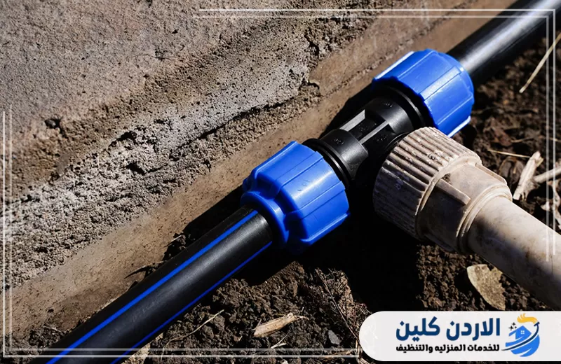 وصلة ضغط زرقاء تربط ماسورة مياه بولي إيثيلين سوداء بخط آخر لضمان اتصال ثابت وتقليل احتمالات التسرب.