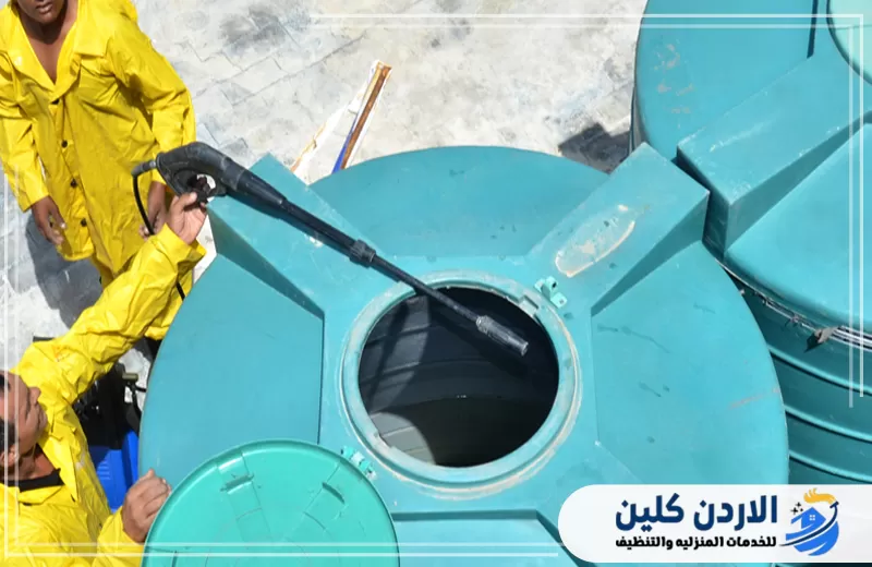 فريق ينفذ تنظيف خزان مياه من الفتحة العلوية باستخدام ضغط المياه لإزالة الرواسب والأوساخ من الداخل.