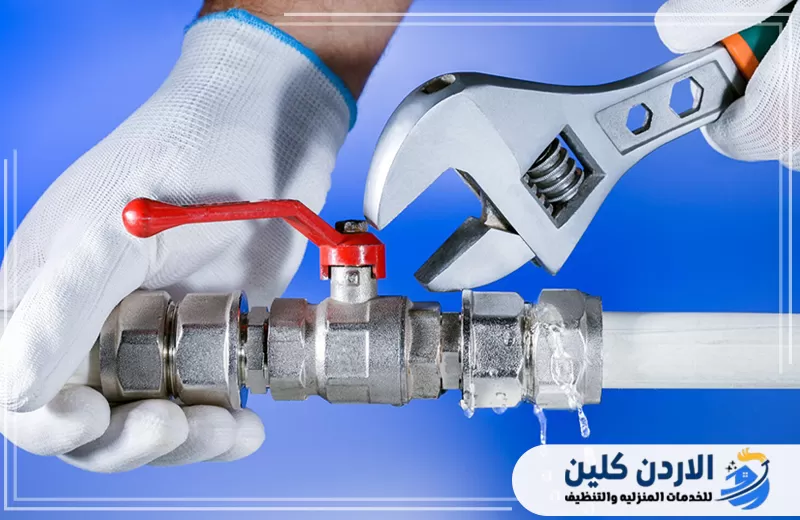 فني يقوم بإصلاح وصلة مياه متسربة باستخدام مفتاح إنجليزي مع ظهور قطرات التسرب عند الوصلة.